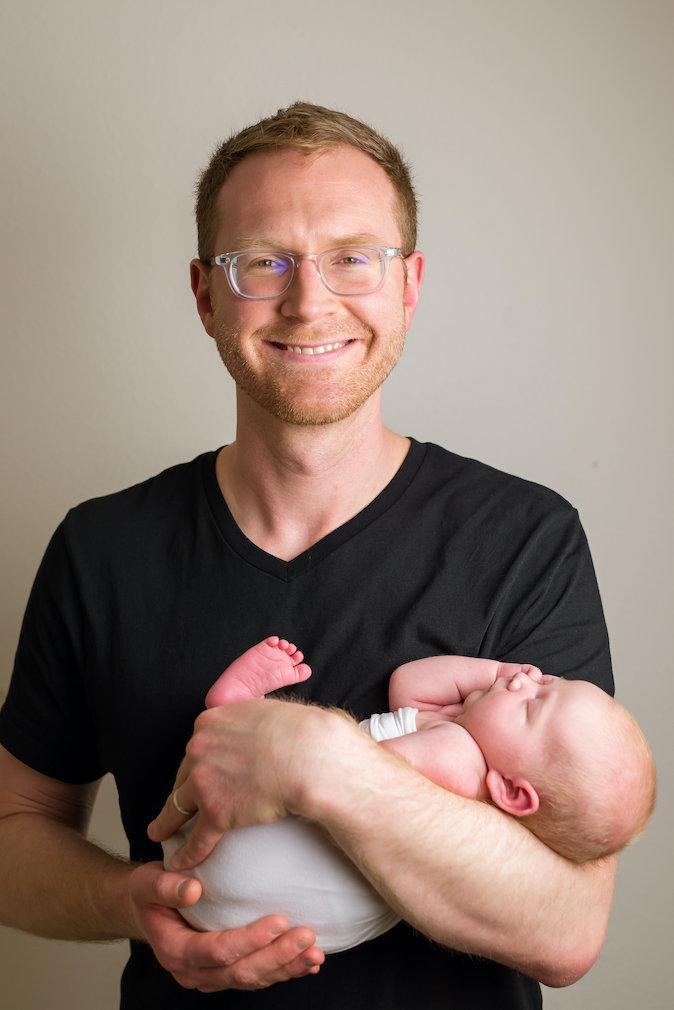 A photo of the author looking very tired and holding his newborn daughter, Elena